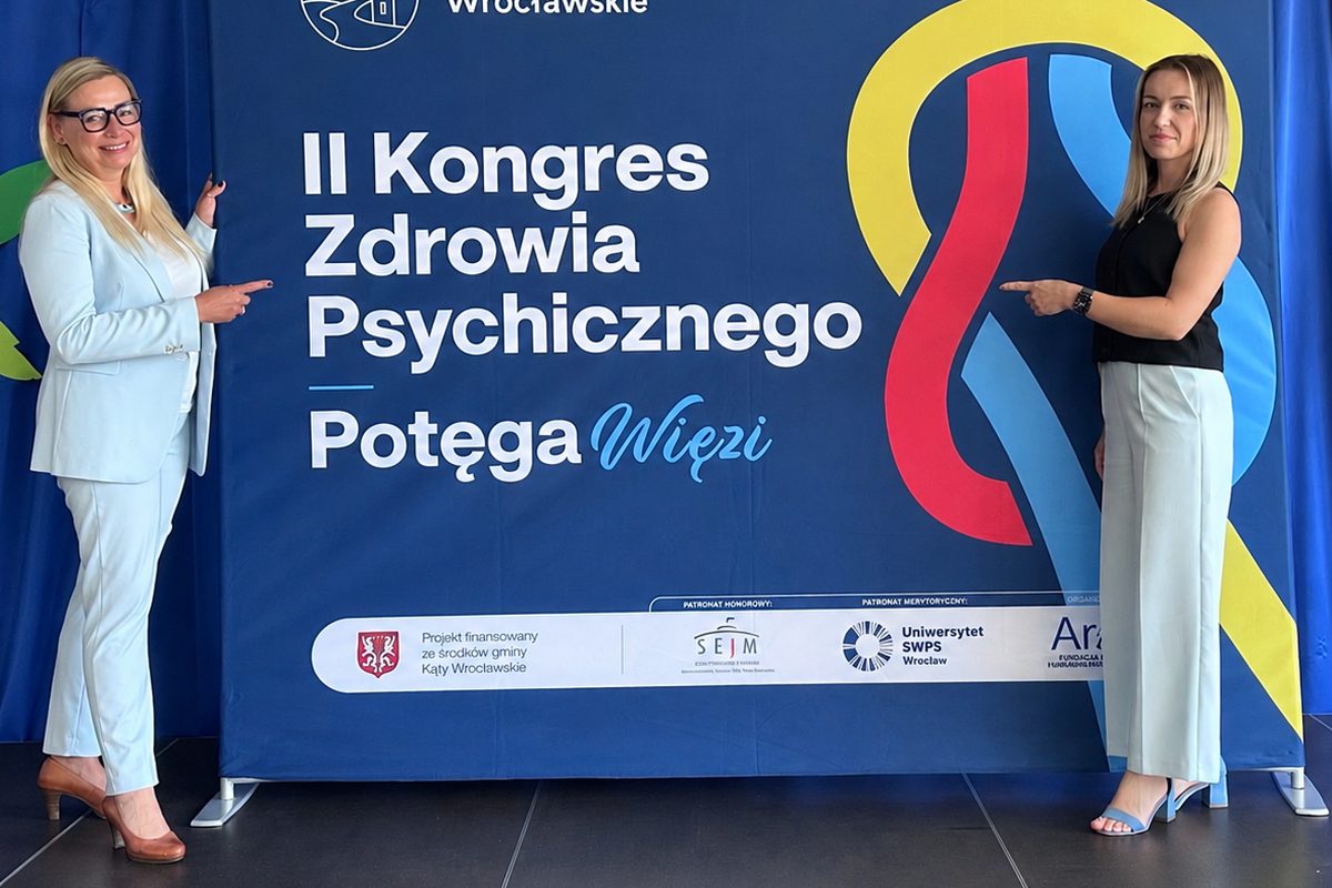 Dwie osoby z Fundacji Arvo przed banerem II Kongresu Zdrowia Psychicznego „Potęga więzi”